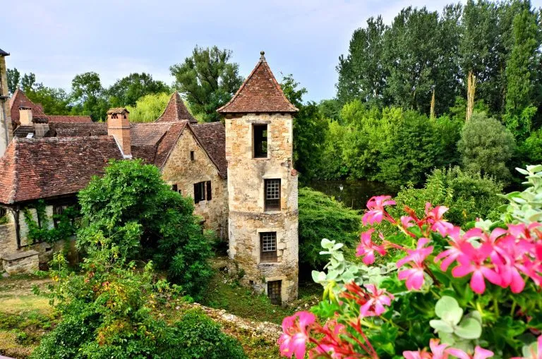 Altes mittelalterliches Haus und Turm mit Blumen in dem malerischen Dorf Carennac, Frankreich