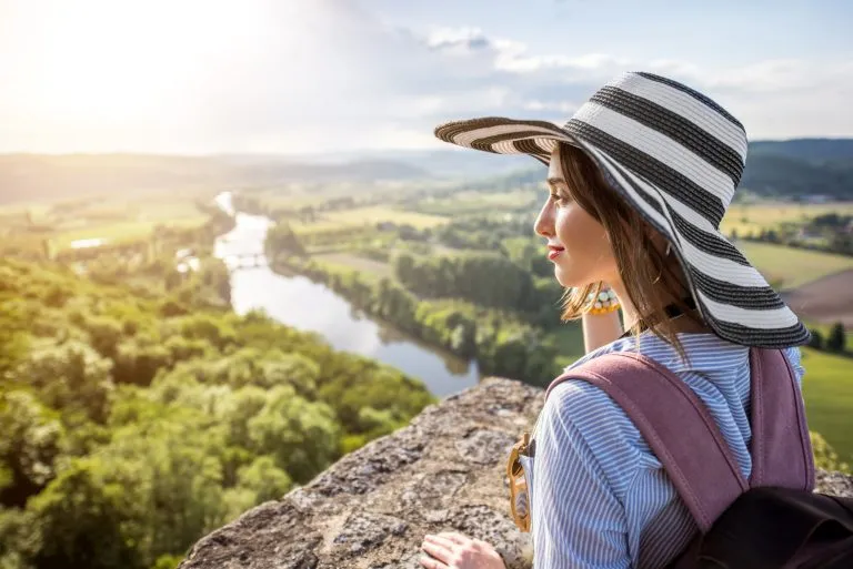 Junge Frau Tourist in Hut genießen Sonnenuntergang Blick auf die schöne Landschaft mit Dordogne Fluss in Frankreich